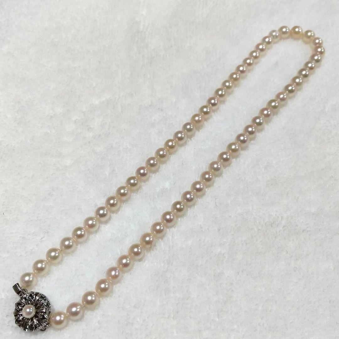 Akoya pearl necklace with 4-7mm white pearls and silver stamp clasp on a white background