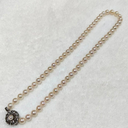 Akoya pearl necklace with 4-7mm white pearls and silver stamp clasp on a white background