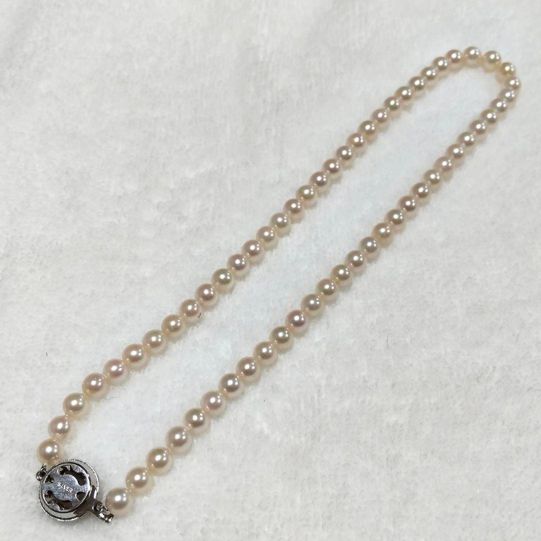 Akoya pearl necklace with 4-7mm white pearls and silver stamp clasp on a white background