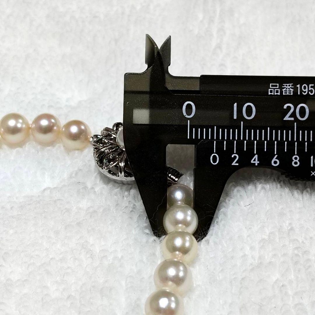 Akoya pearl necklace with 4-7mm white pearls and silver stamp clasp on a white background