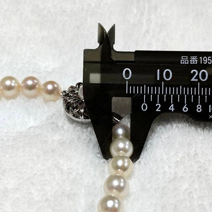 Akoya pearl necklace with 4-7mm white pearls and silver stamp clasp on a white background