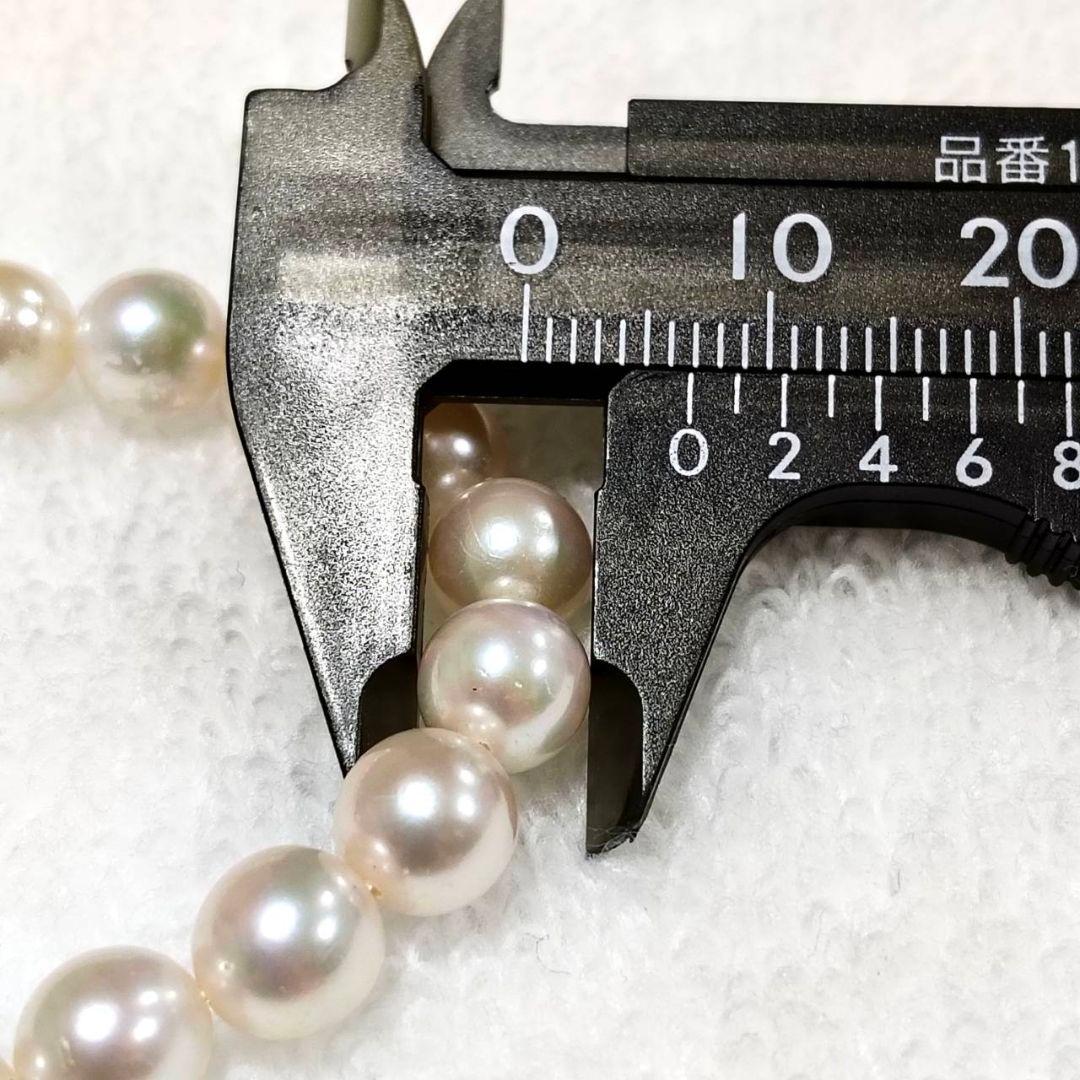 Akoya pearl necklace with 4-7mm white pearls and silver stamp clasp on a white background