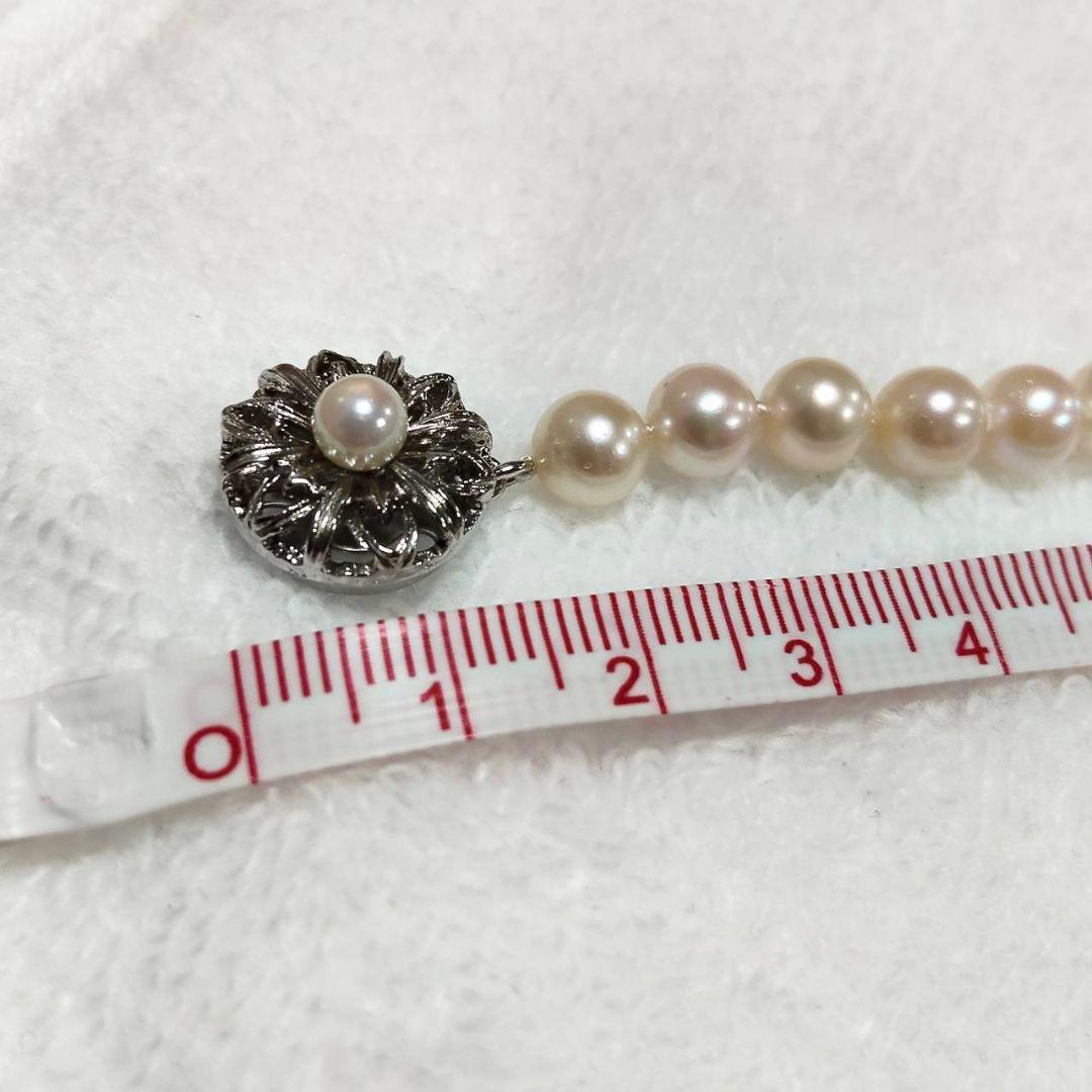 Akoya pearl necklace with 4-7mm white pearls and silver stamp clasp on a white background
