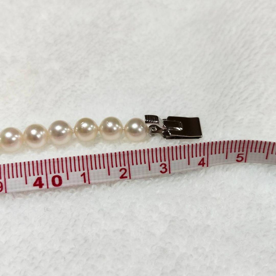 Akoya pearl necklace with 4-7mm white pearls and silver stamp clasp on a white background