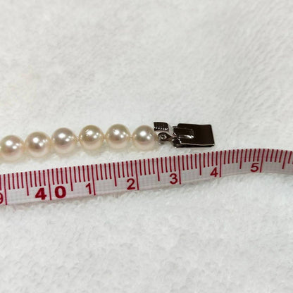 Akoya pearl necklace with 4-7mm white pearls and silver stamp clasp on a white background
