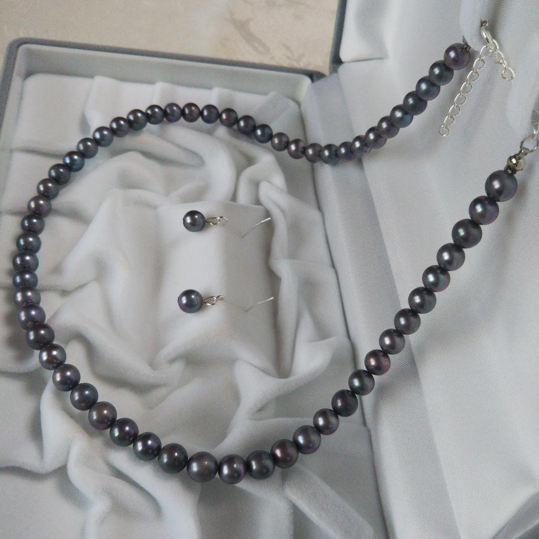 Akoya pearl necklace and matching earrings with silver clasp and findings on white background