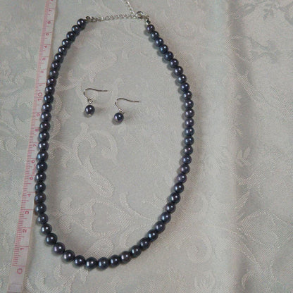 Akoya pearl necklace and matching earrings with silver clasp and findings on white background
