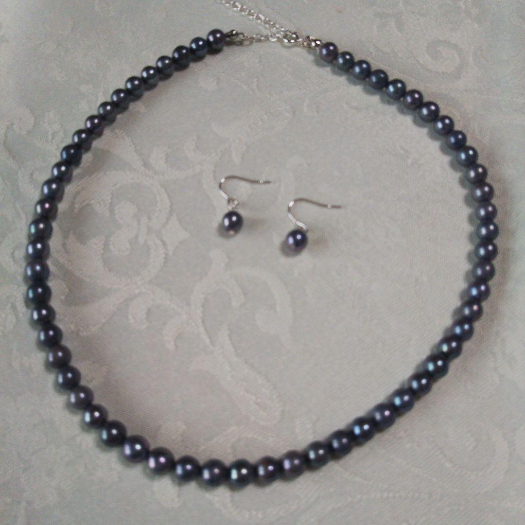 Akoya pearl necklace and matching earrings with silver clasp and findings on white background