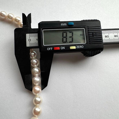 Akoya pearl necklace with white to pink pearls and silver metal fittings displayed on white background