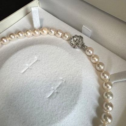 Akoya pearl necklace with white to pink pearls and silver metal fittings displayed on white background