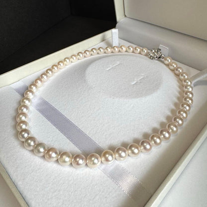 Akoya pearl necklace with white to pink pearls and silver metal fittings displayed on white background