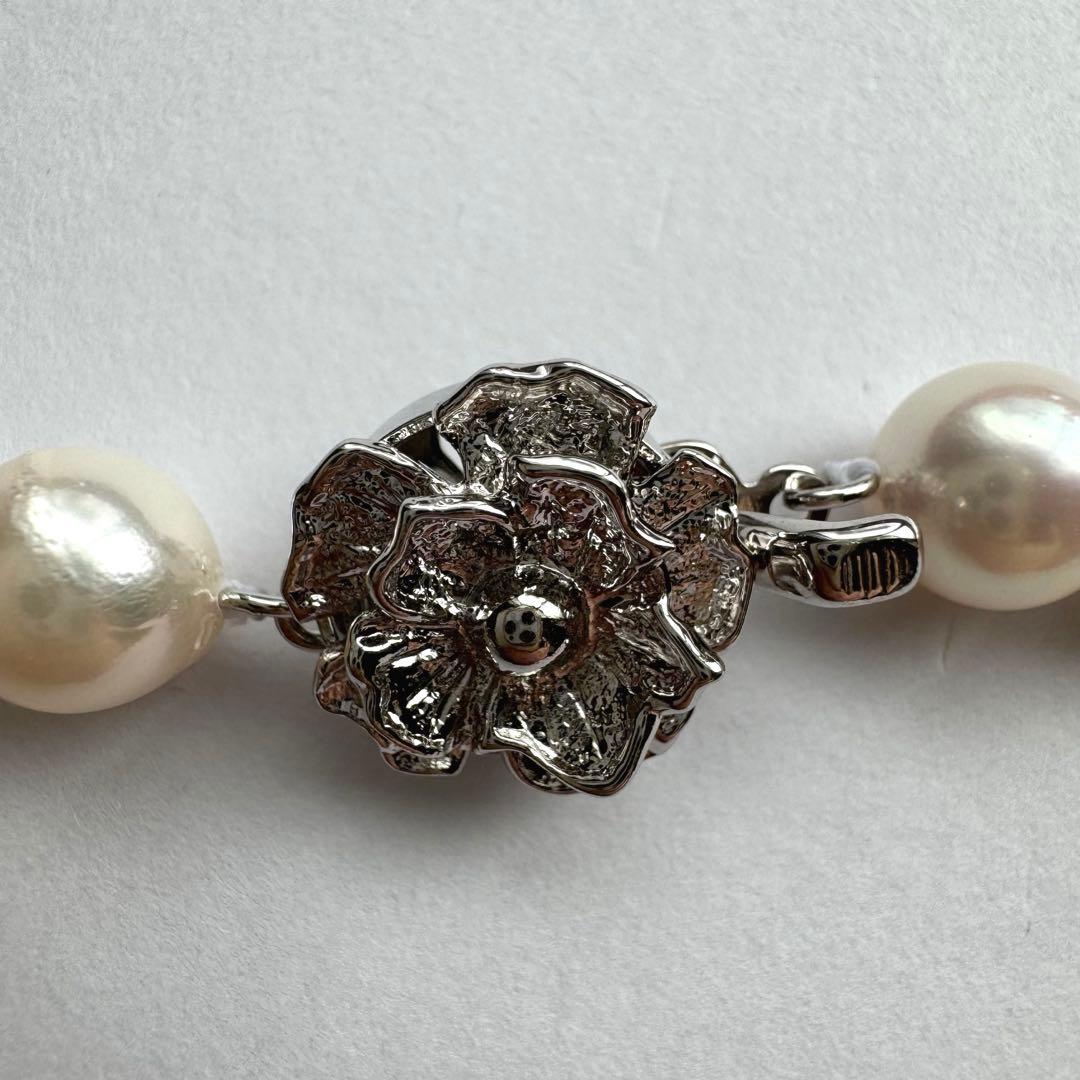 Akoya pearl necklace with white to pink pearls and silver metal fittings displayed on white background