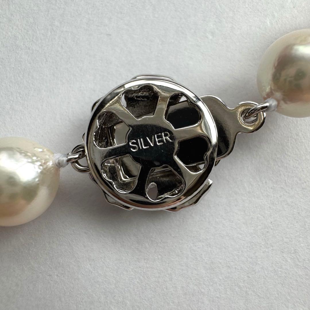 Akoya pearl necklace with white to pink pearls and silver metal fittings displayed on white background