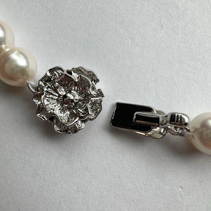 Akoya pearl necklace with white to pink pearls and silver metal fittings displayed on white background