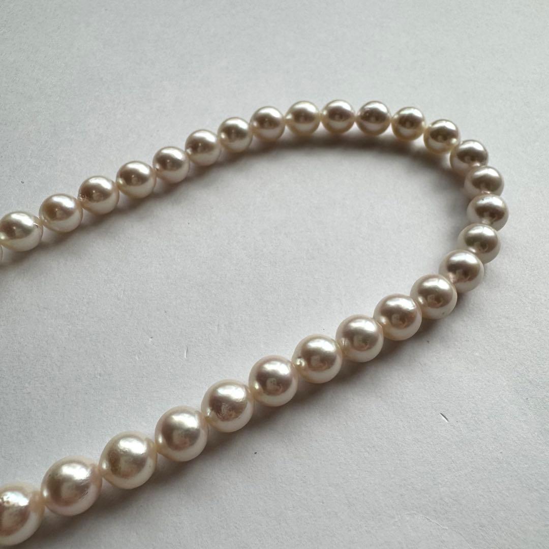 Akoya pearl necklace with white to pink pearls and silver metal fittings displayed on white background