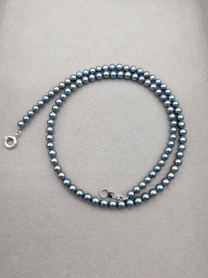 Akoya cultured pearl baby necklace with black peacock tone pearls and silver clasp on white background