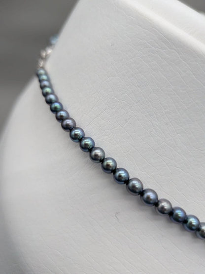Akoya cultured pearl baby necklace with black peacock tone pearls and silver clasp on white background