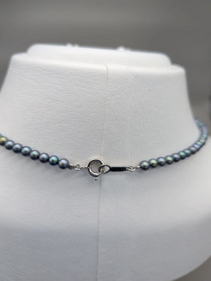 Akoya cultured pearl baby necklace with black peacock tone pearls and silver clasp on white background