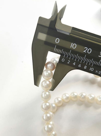 Akoya Pearl Necklace featuring 7 mm white pearl beads, 42 cm length, laid out on a white background