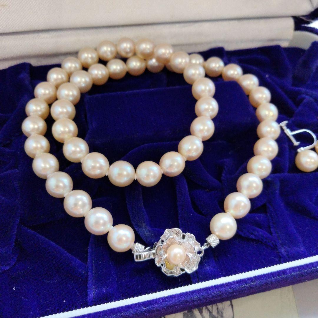 Akoya pearl necklace and matching earrings set with white pearls and silver clasp on a white background