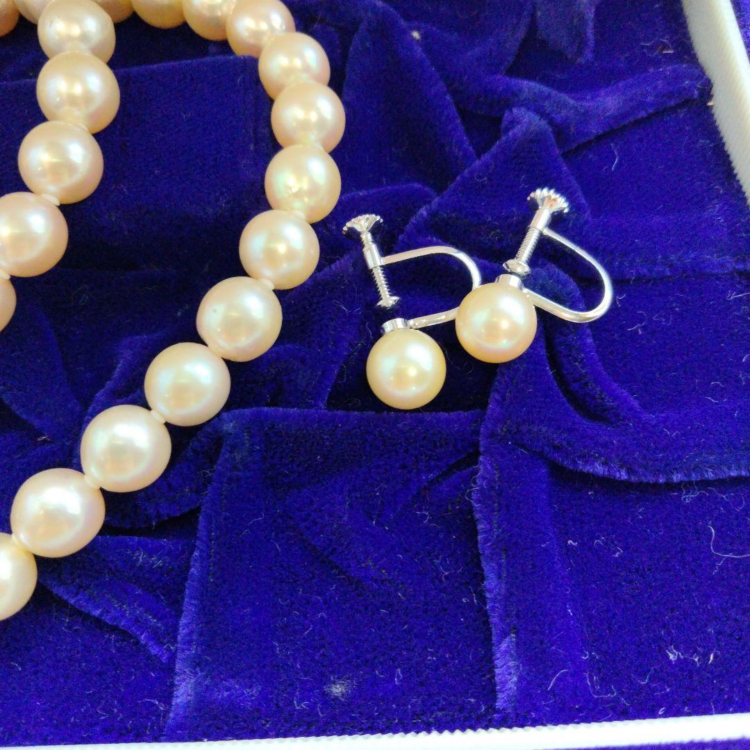 Akoya pearl necklace and matching earrings set with white pearls and silver clasp on a white background