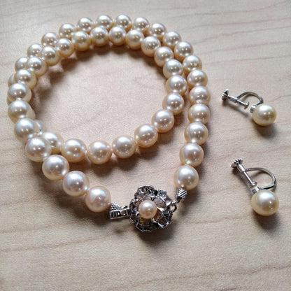 Akoya pearl necklace and matching earrings set with white pearls and silver clasp on a white background