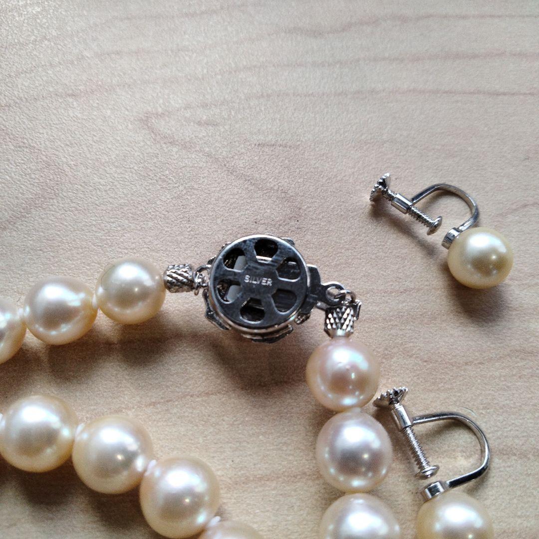 Akoya pearl necklace and matching earrings set with white pearls and silver clasp on a white background