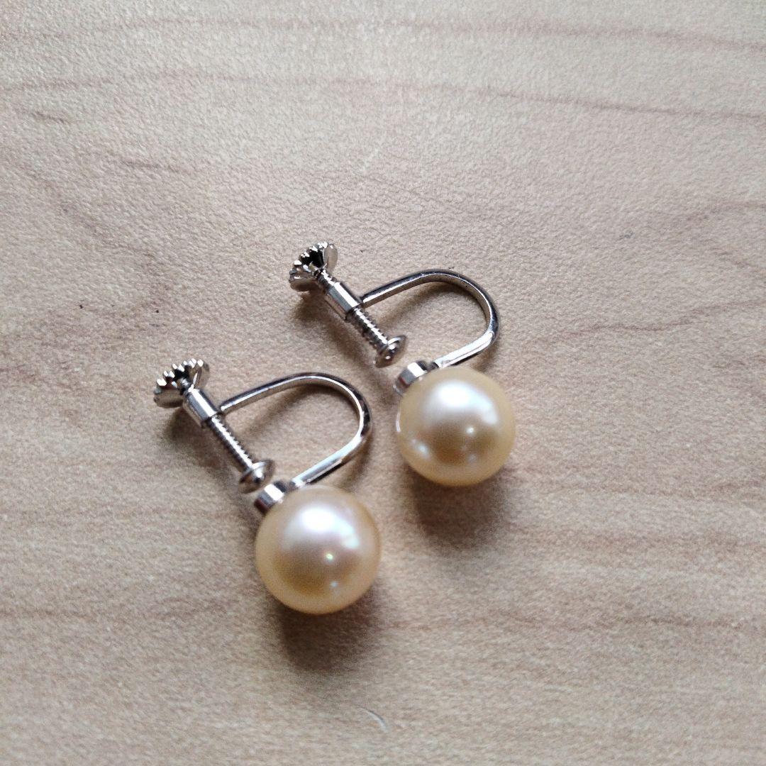 Akoya pearl necklace and matching earrings set with white pearls and silver clasp on a white background