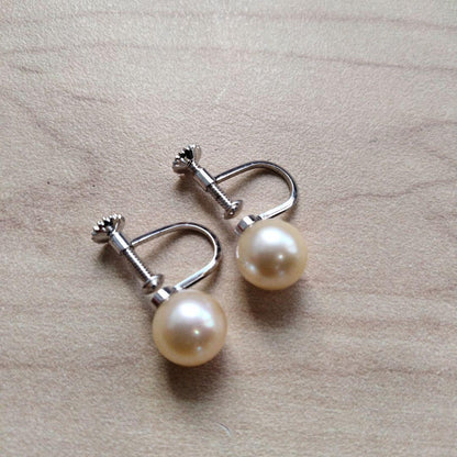 Akoya pearl necklace and matching earrings set with white pearls and silver clasp on a white background