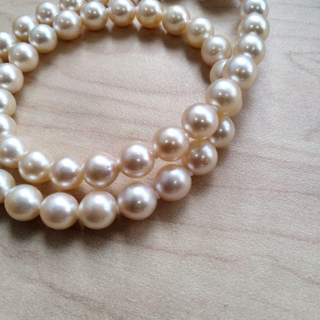 Akoya pearl necklace and matching earrings set with white pearls and silver clasp on a white background