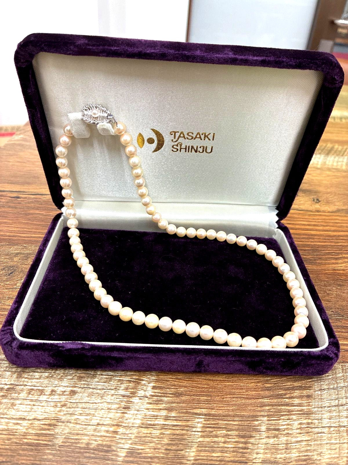 Used TASAKI pearl necklace with imprint displayed alongside its case