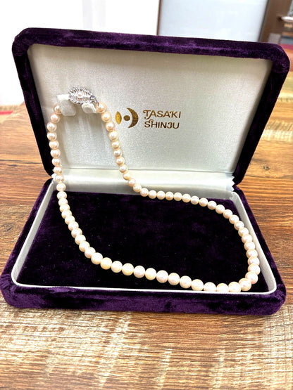 Used TASAKI pearl necklace with imprint displayed alongside its case