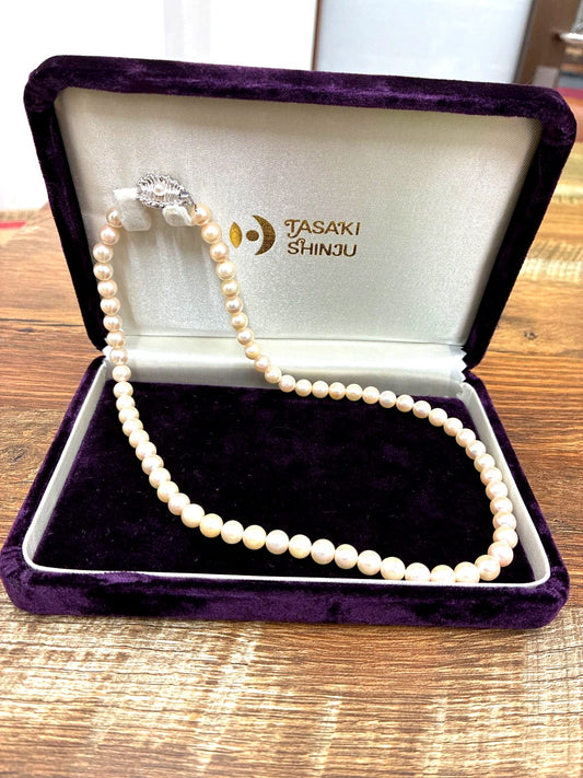 Used TASAKI pearl necklace with imprint displayed alongside its case