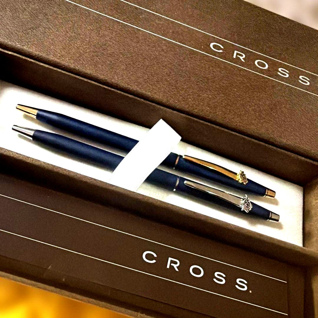 Cross 2-piece ballpoint pen set in gold and silver with navy accents, displayed with gift box and manual