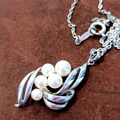 Mikimoto pearl necklace with grape-colored pearls and slightly discolored chain displayed on white background