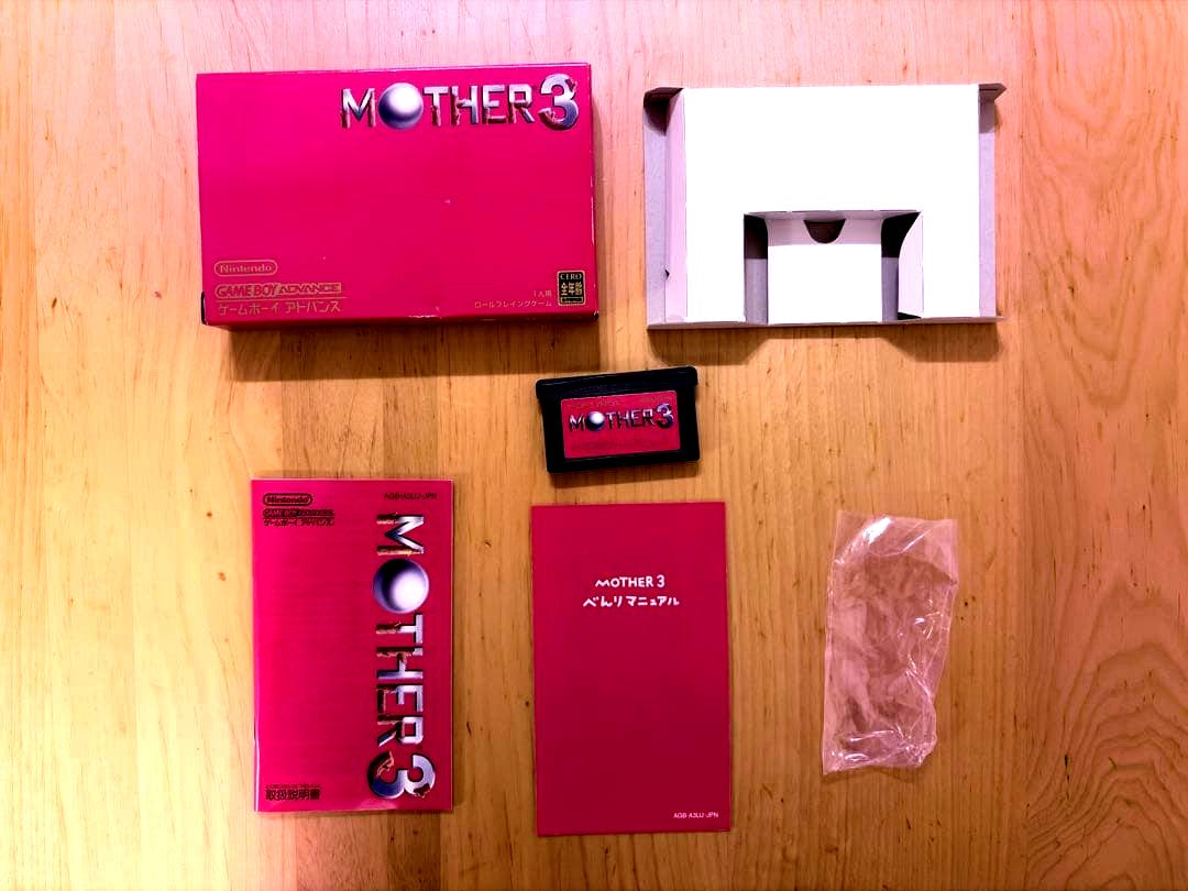 MOTHER3 Game Boy Advance game with outer box, inner box, and instruction manual showing slight box tears