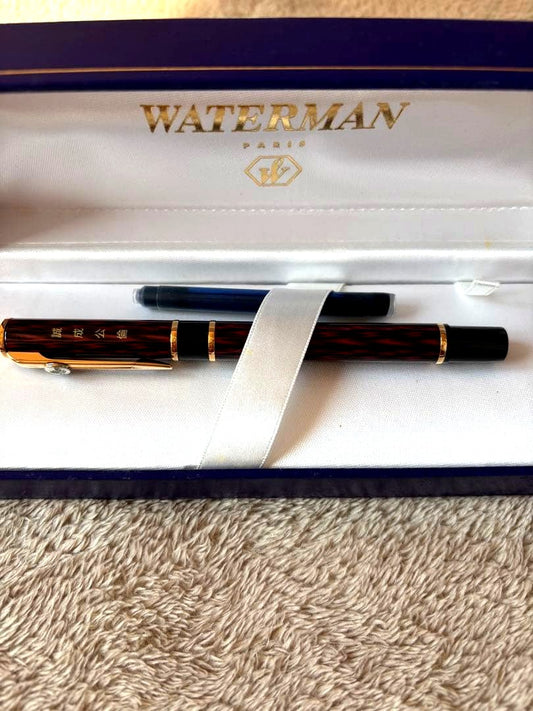 Brown WATERMAN fountain pen with logo, presented alongside a protective case and extra ink bottle