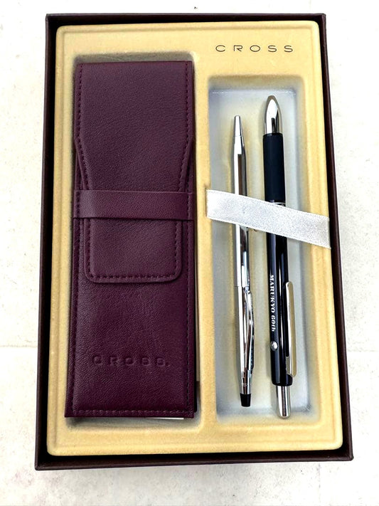 Two CROSS ballpoint pens in silver and black alongside a leather-like pen case