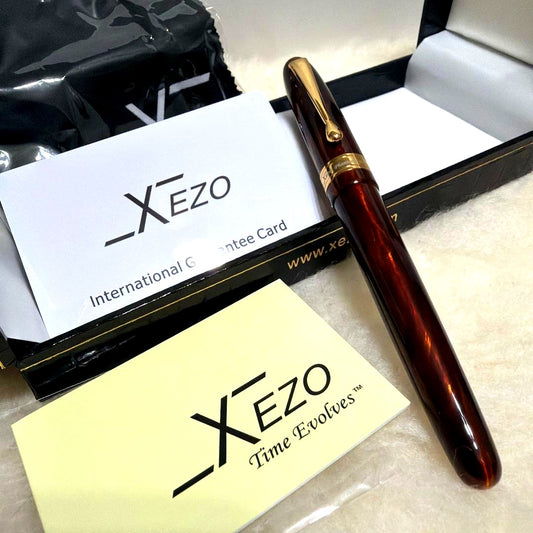 Xezo Handmade fountain pen body in reddish brown with gold accents, displayed with gift box, cross, and guarantee card