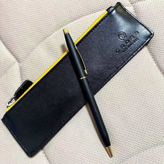 Cross ballpoint pen with matte black body and gold accents displayed with yellow interior case