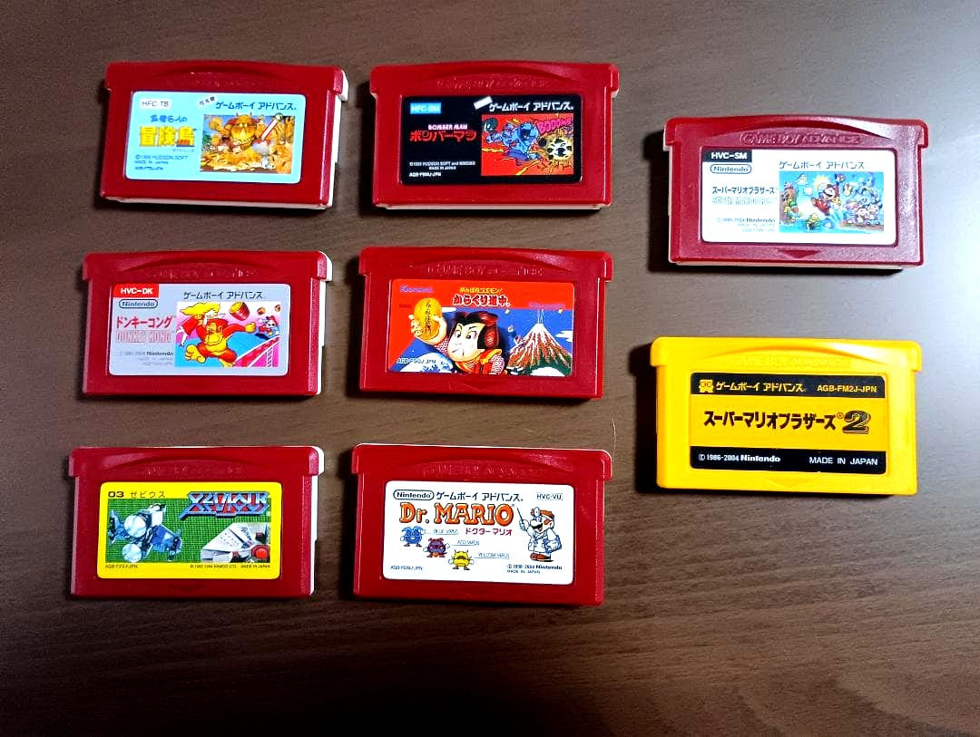 Famicom Mini Advance console with 8 classic game cartridges including Takahashi Meijin's Adventure Island and Bomberman