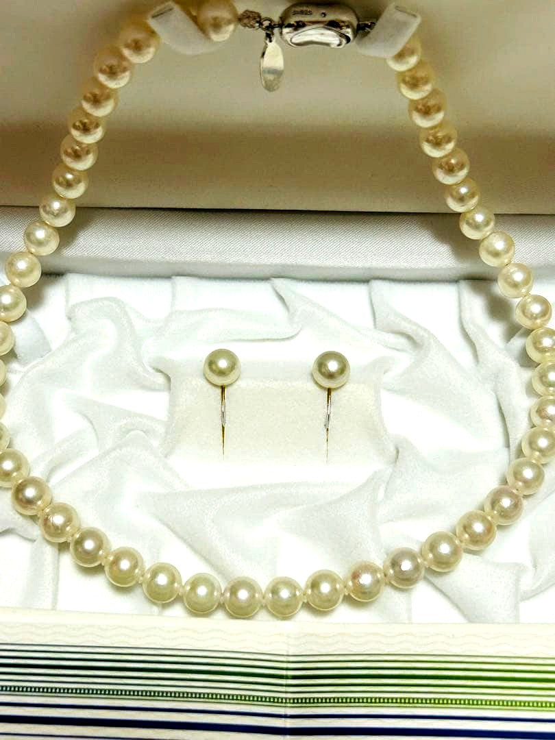 Akoya pearl choker necklace with matching pair of pearl earrings on white background