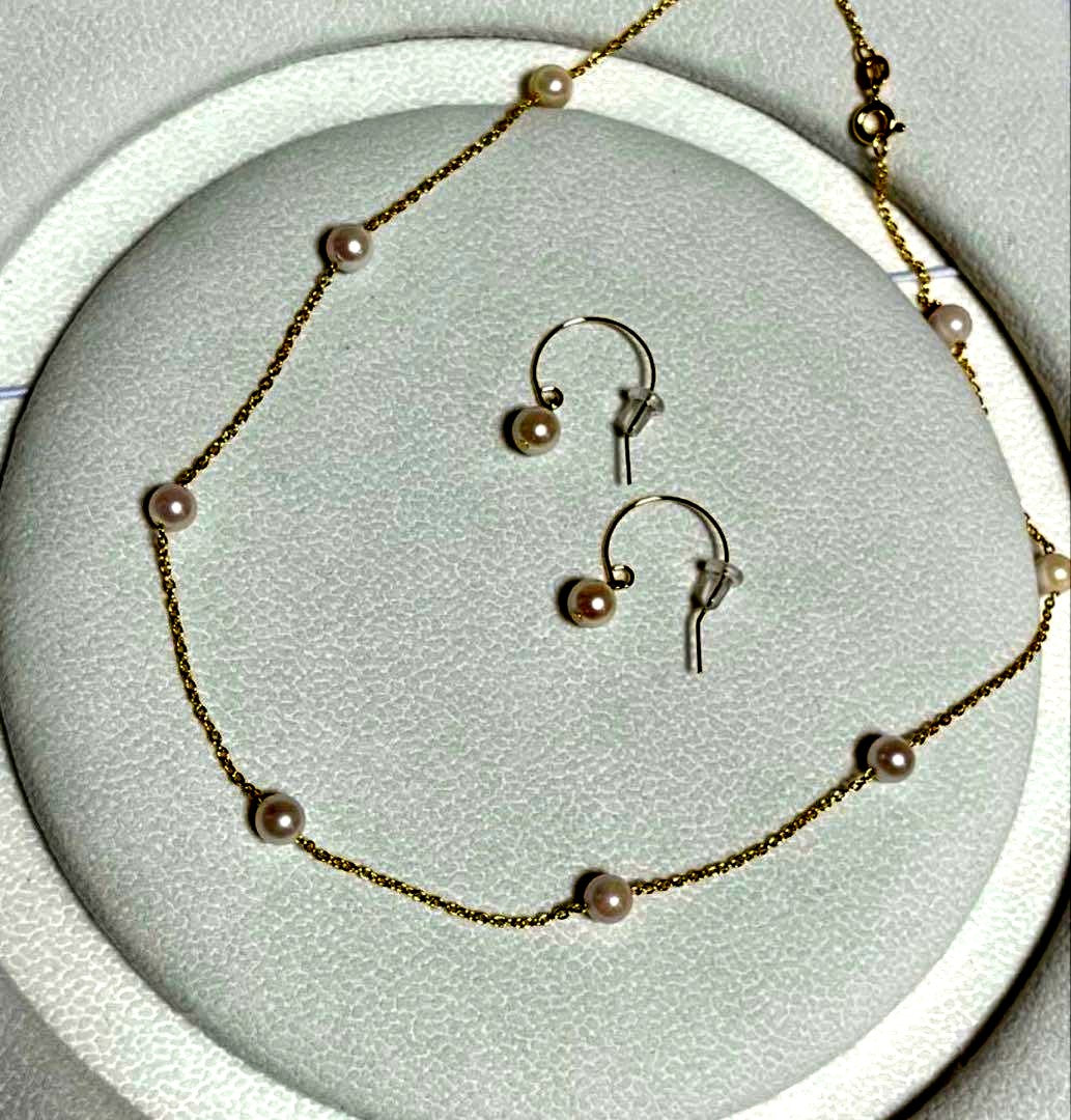 Akoya pearl station necklace with 9 white pink pearls and matching silver hook earrings set on white background