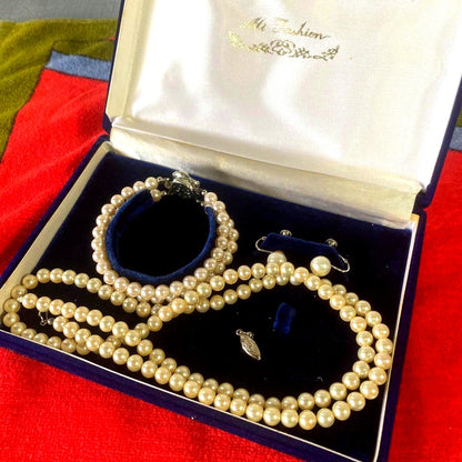 Akoya pearl necklace, matching earrings, and bracelet displayed on a white background