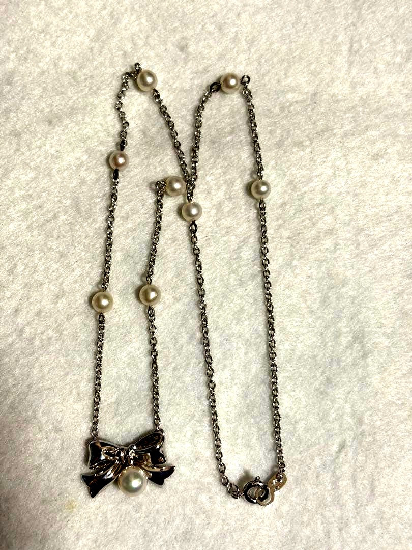 TASAKI elegant silver necklace with lustrous white pearls on a white background