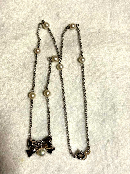 TASAKI elegant silver necklace with lustrous white pearls on a white background