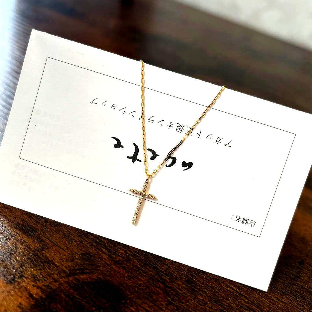 agete K18YG yellow gold diamond cross necklace with reversible milgrain design on a white background