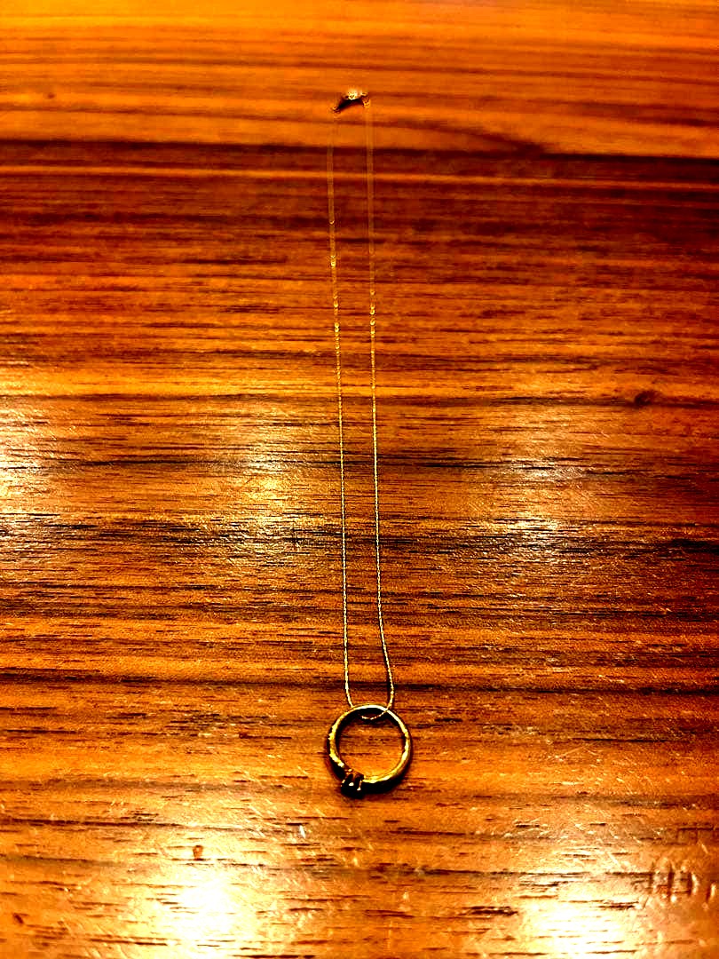Mikimoto gold necklace with a sapphire pendant displayed on a white background