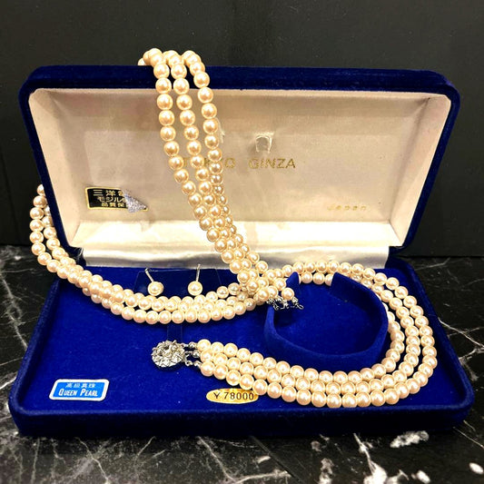 Akoya pearl three-strand beige necklace with matching earrings displayed on a white background