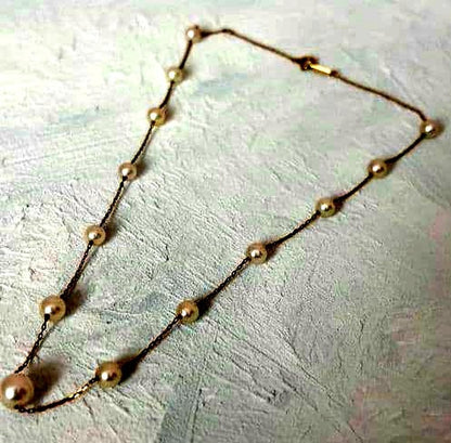 Beautiful K18 gold chain Akoya pearl necklace with 13 round pearls sized 6.5 to 9.5 mm on a white background